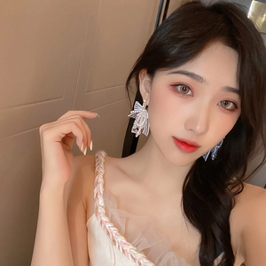 Boucles d'oreilles nœud en dentelle blanche avec perles et longs pompons sur un mannequin