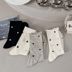 Breathable polka dot crew socks in four classic colors on a minimalist grey backdrop
