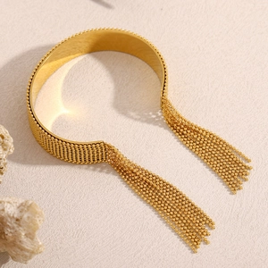 Detail of 18K gold plated wide cuff bracelet featuring delicate bead chain tassels