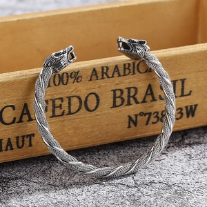 Detailed close-up of vintage silver twin wolf heads on a steel wire twisted cuff bracelet
