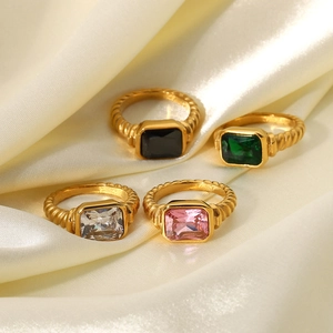 Golden twisted croissant rings with rectangle emerald, pink, and black gemstones on silk