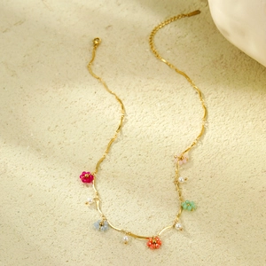 Collier doré avec fleurs en perles colorées et perles blanches sur fond clair