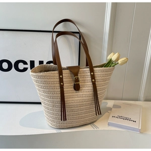 Close-up of a large straw tote bag featuring brown leather straps and white tulips inside