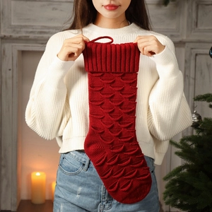 Large red knitted Christmas stocking with fish scale pattern for festive fireplace decor