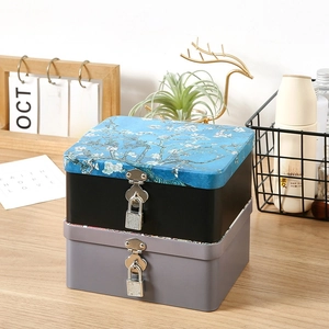 Vintage tin storage box with lock and almond blossom pattern on a wooden desk