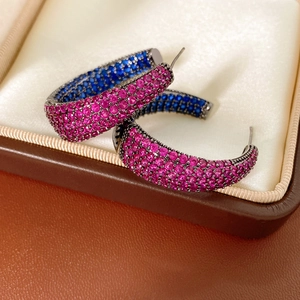 Detail of vintage C-shaped earrings with magenta and deep blue crystals in black setting
