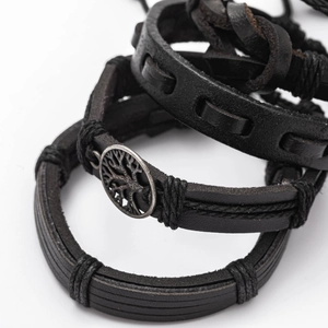 Detail of vintage layered leather bracelets with woven straps and a metal tree of life charm