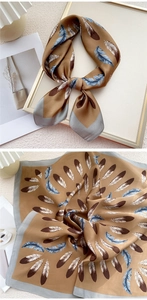 Détail d'un foulard carré en soie kaki avec motifs plumes bleues et bordure grise