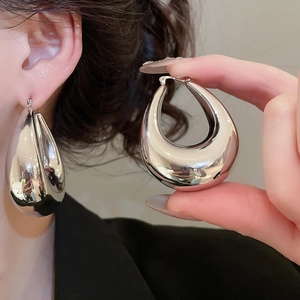 Macro shot of large polished silver teardrop earrings with high-gloss metallic finish