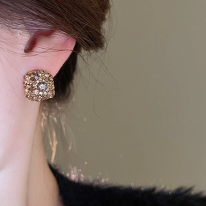 Macro close-up of champagne crystal square stud earrings worn by a model
