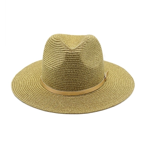 Dettaglio di un cappello di paglia a tesa larga con seta dorata e fascia in pelle marrone