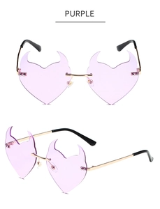 Detail view of purple heart-shaped rimless devil sunglasses with metal frame and horn design