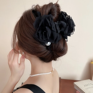 Détail d'une pince à cheveux rose en résille noire avec perles sur un chignon élégant