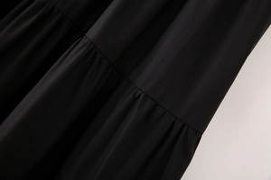 Détail des plis superposés et de la texture du coton sur une robe midi noire