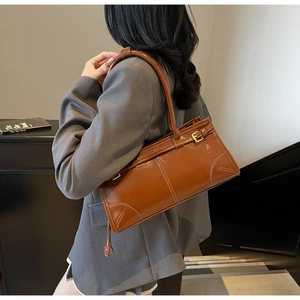 Detail view of brown tote bag showing smooth texture, stitch finish and metal buckle