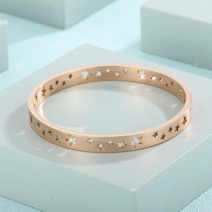 Macro shot of rose gold star-cutout bangle with polished finish and starry hollow patterns