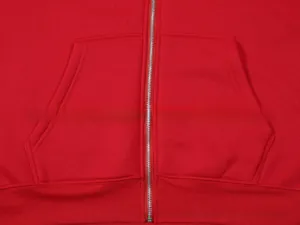 Detail view of red zip-up hoodie featuring metal zipper and symmetrical side pockets