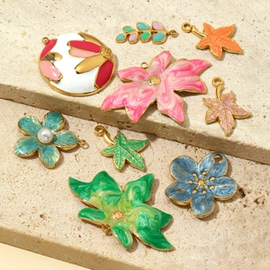 Colorful floral and leaf titanium steel pendants with pearl accents on beige sandstone