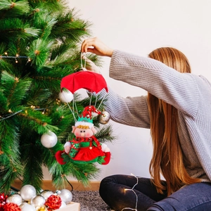 Christmas parachute elf doll hanging on a festive Xmas tree with red and green decor