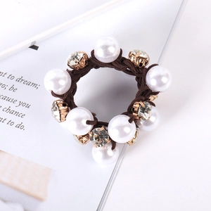 Detailed macro view of brown elastic hair tie with white pearls and sparkling rhinestones