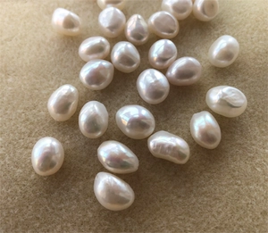 Macro display of natural white baroque freshwater pearls with lustrous finish on beige felt