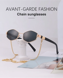 Detailed view of hexagonal sunglasses with black lenses and decorative gold chain