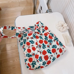 Detailed close-up of floral print canvas tote bag with red roses on white fabric