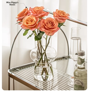 French vintage tiered glass vase with orange roses on a chrome storage cart