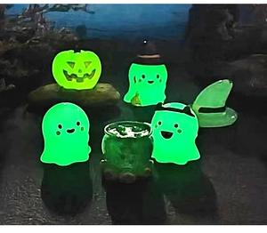 Macro view of six luminous Halloween miniature ghosts and pumpkin figurines glowing in dark
