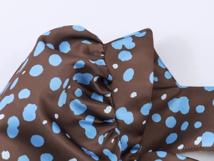 Close-up of elegant coffee brown satin fabric with blue polka dots and pleated details