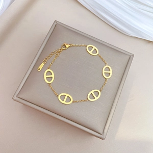 Elegant gold stainless steel pig nose link bracelet on a luxury grey jewelry cushion
