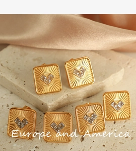 Detailed close-up of golden square stud earrings with heart zirconia on silk fabric