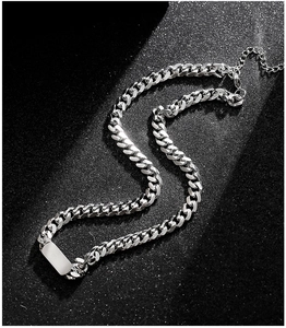 Macro detail of silver Cuban link necklace with rectangular tag and extension chain