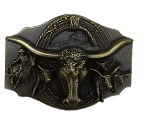 Detail of vintage western belt buckle featuring a bronze bull skull and cowboy relief