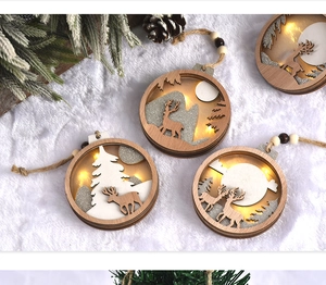 Close-up of a lit wooden Christmas ornament featuring an elk and snowy pine forest detail
