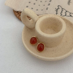 Macro view of vintage oval red agate stud earrings with golden metallic frames