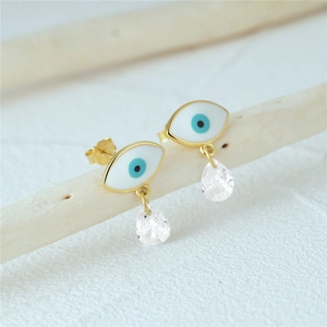 Detail of evil eye earrings with gold finish and water drop zircon on wooden branch