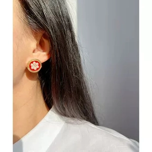 Gros plan de boucles d'oreilles émaillées rouges dorées avec perles sur un mannequin