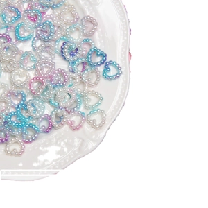 Gradient heart-shaped pearl beads in blue and purple on a white decorative dish