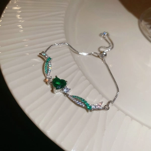 Macro detail of silver adjustable heart bracelet with green zircon and sparkling stones