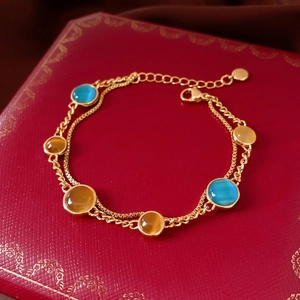 Detail of 18k gold plated double chain bracelet with amber and blue cat-eye stones