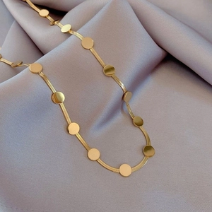 Collier chaîne serpent dorée avec disques circulaires sur tissu en soie violet élégant