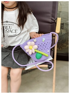 Detail of a purple woven kids crossbody bag with decorative pearls and floral patterns