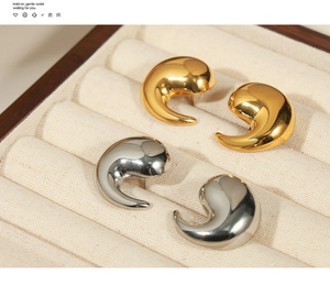 Detailed view of polished teardrop earrings in gold and silver finish on a gift box