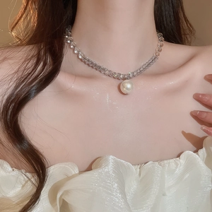 Close-up of a pearl pendant necklace with clear crystal beads worn by a model