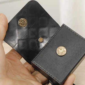 Detail of the black pebbled leather mini pouch showing the golden magnetic closure buckle
