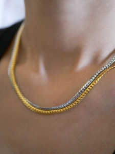 Close-up of layered gold and silver snake chain necklace on neck with polished metallic finish