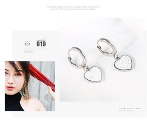 Detail view and model shot of heart-shaped earrings with white glitter enamel in silver