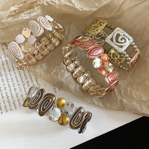 Detail showing bohemian elastic bracelets with enamel inlay and hollow heart metal charms
