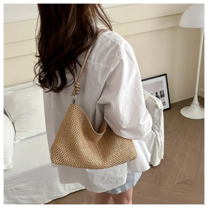 Detail of hand-woven straw tote bag with knotted PU shoulder strap on a model